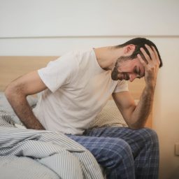 Tired man sitting on the edge of his bed.