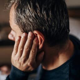 Man with an earache putting his hand to his ear.