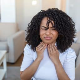 Young woman rubbing her sore throat.