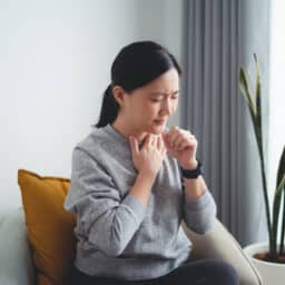 Woman with a hand on her chest with a sore throat