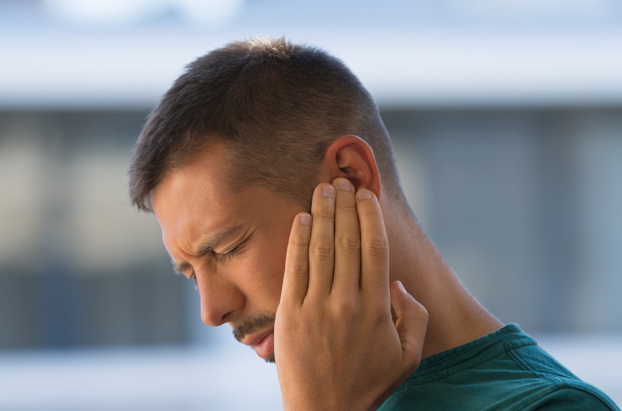 Man with ear pain holds ear