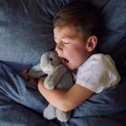 Young boy yawns in bed