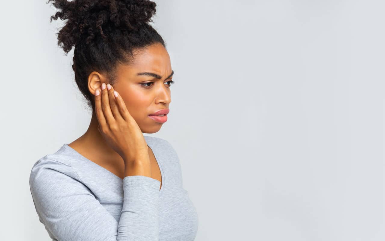 Woman holds ear in pain.